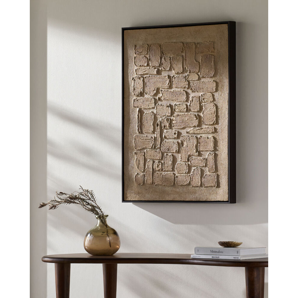 Abstract wall art piece on a neutral wall with a table and vase in the foreground.