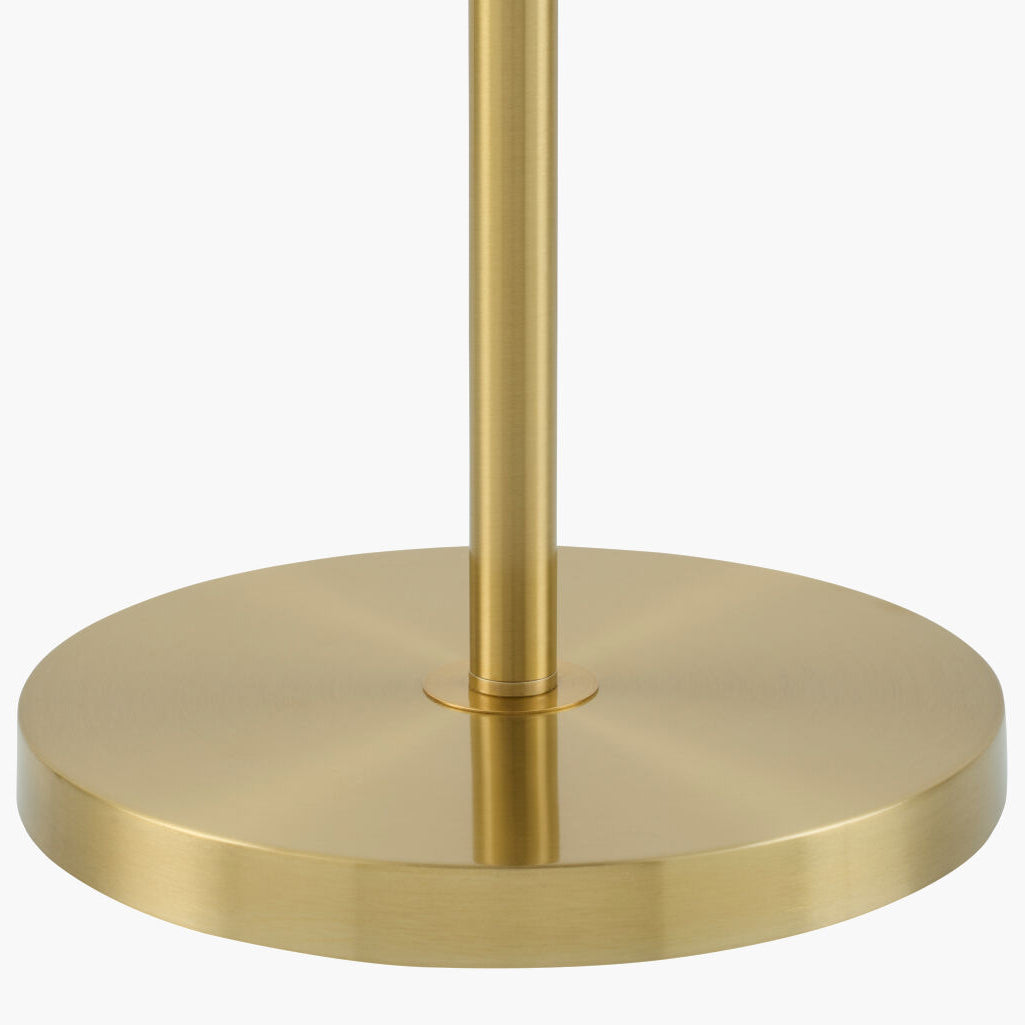 Close-up of a brushed brass or gold metal lamp base with a vertical stem rising upward against a plain white background.