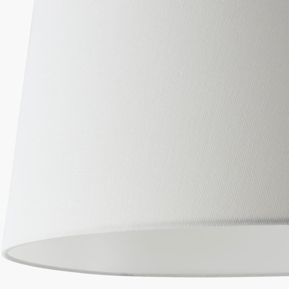 Close-up of a white linen lampshade showing its fine woven texture and curved bottom edge against a white background.