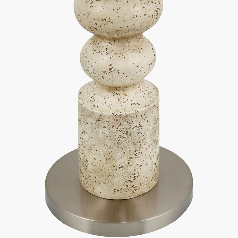 A close-up of a decorative table lamp base featuring a textured cream and beige stone column with dark speckles, mounted on a round brushed silver metal base, set against a plain white background.