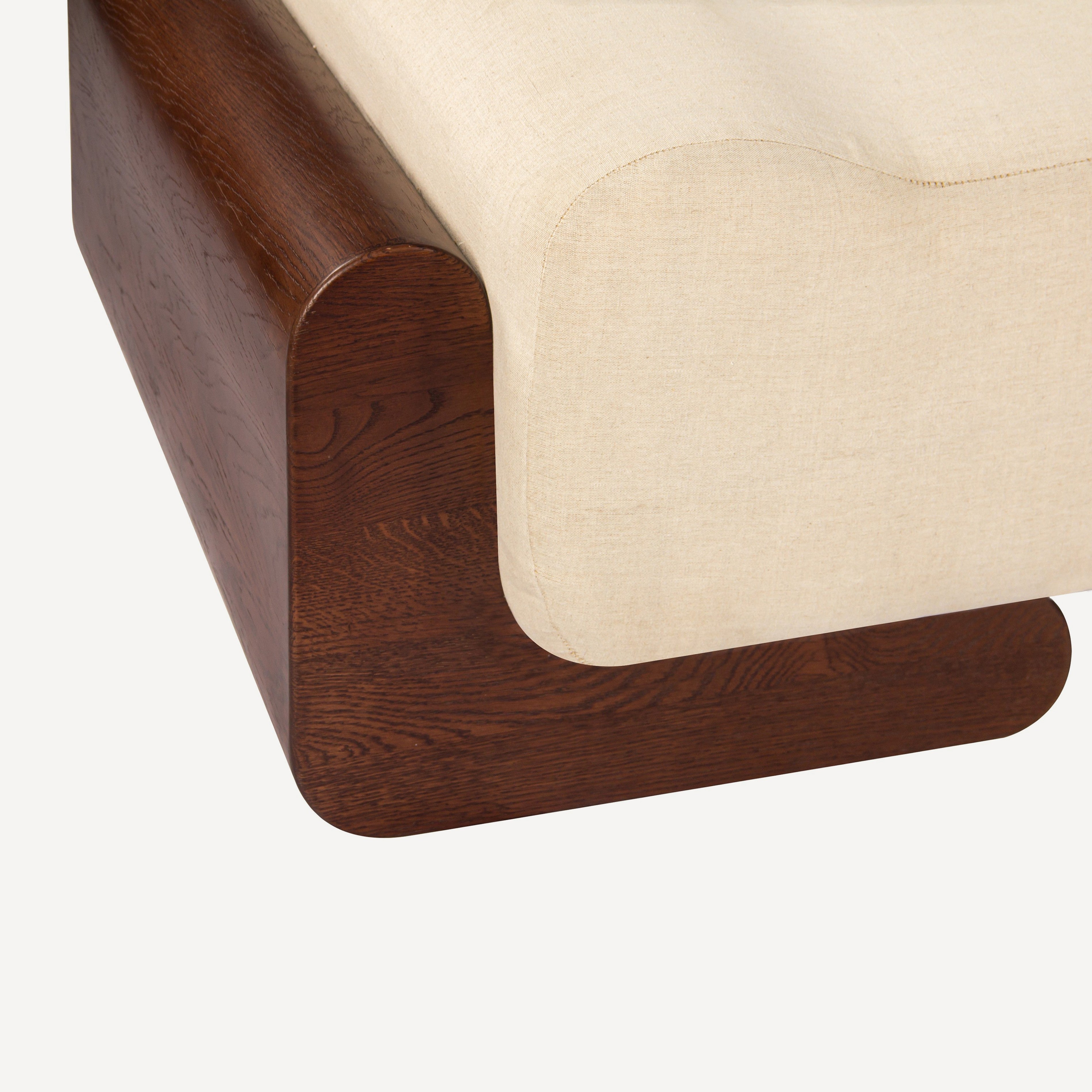 Close-up of a modern upholstered chair or bench corner, showing a dark brown wood frame with rounded edges and a light beige textured fabric seat on a plain light background.