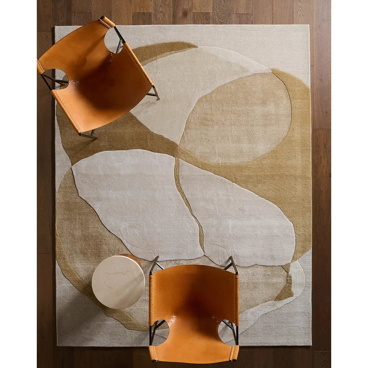 Abstract patterned rug with two brown chairs on a wooden floor