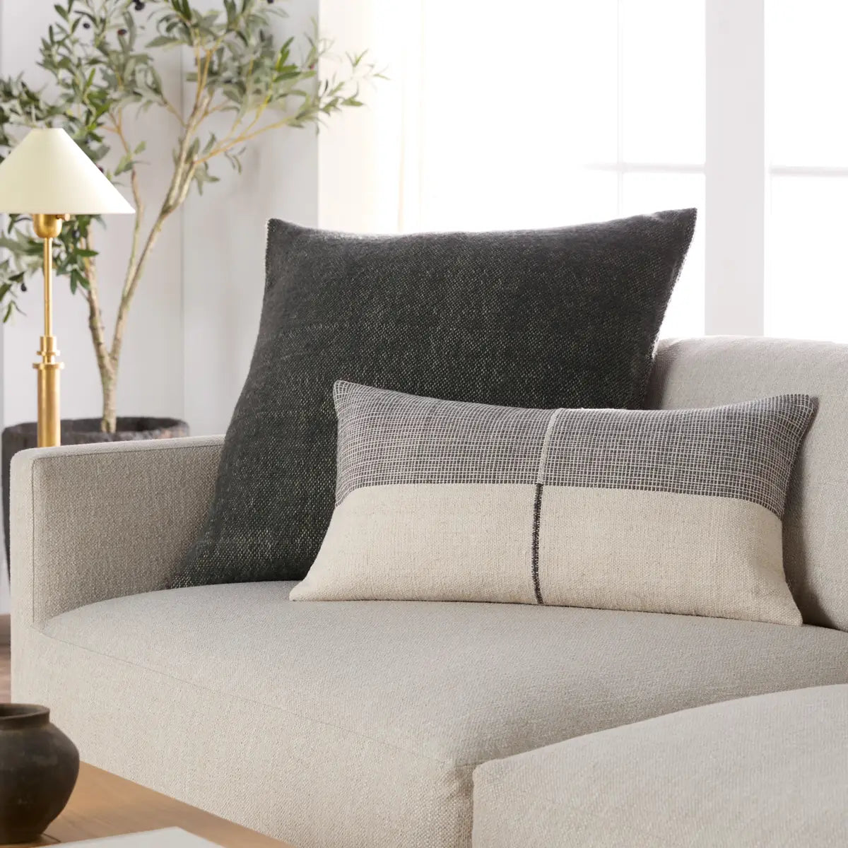Gray and beige pillows on a light gray sofa in a living room setting.