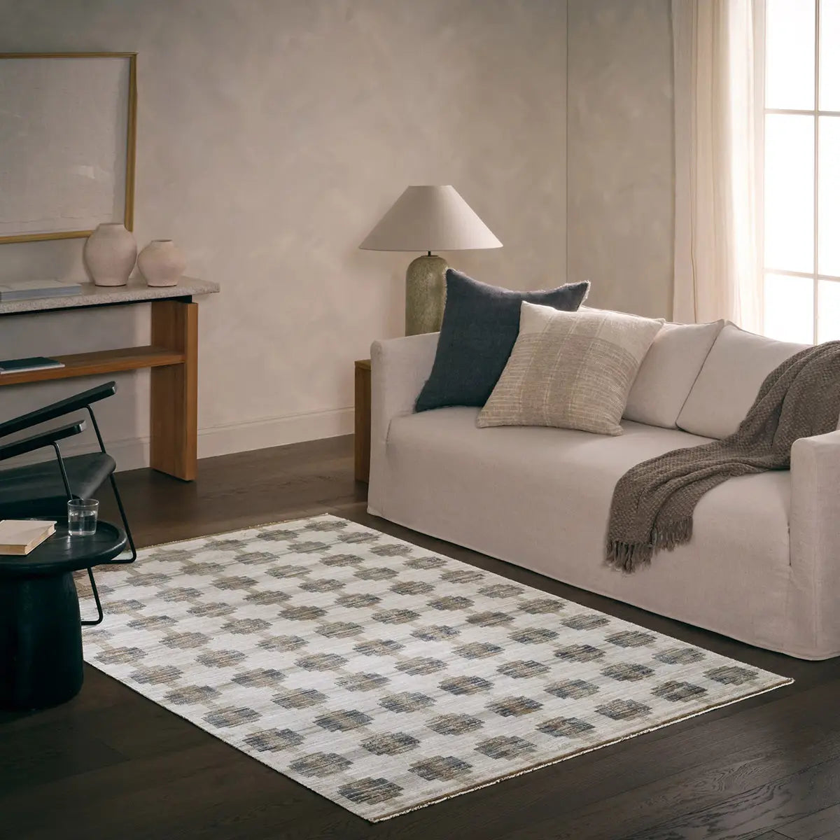 Living room with a beige sofa, patterned rug, and decorative items.