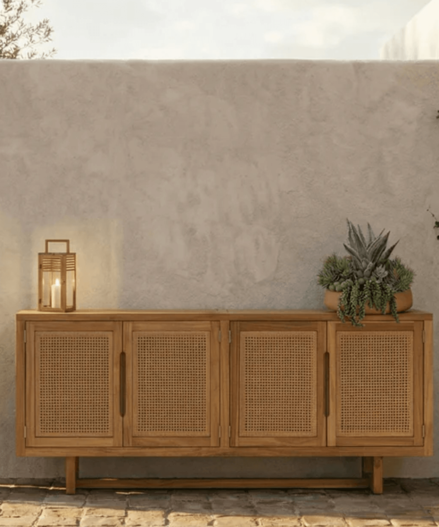 Wooden sideboard with wicker doors against a textured wall.