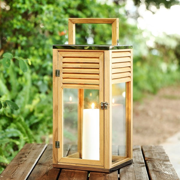 Wooden lantern with a candle inside on a wooden surface outdoors.