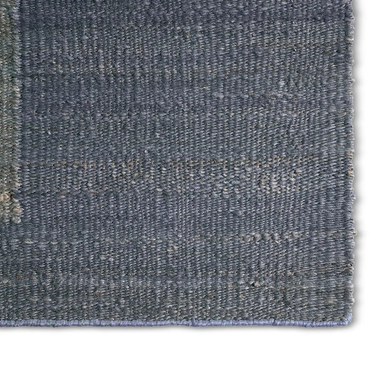 Close-up of a textured blue rug corner on a white background