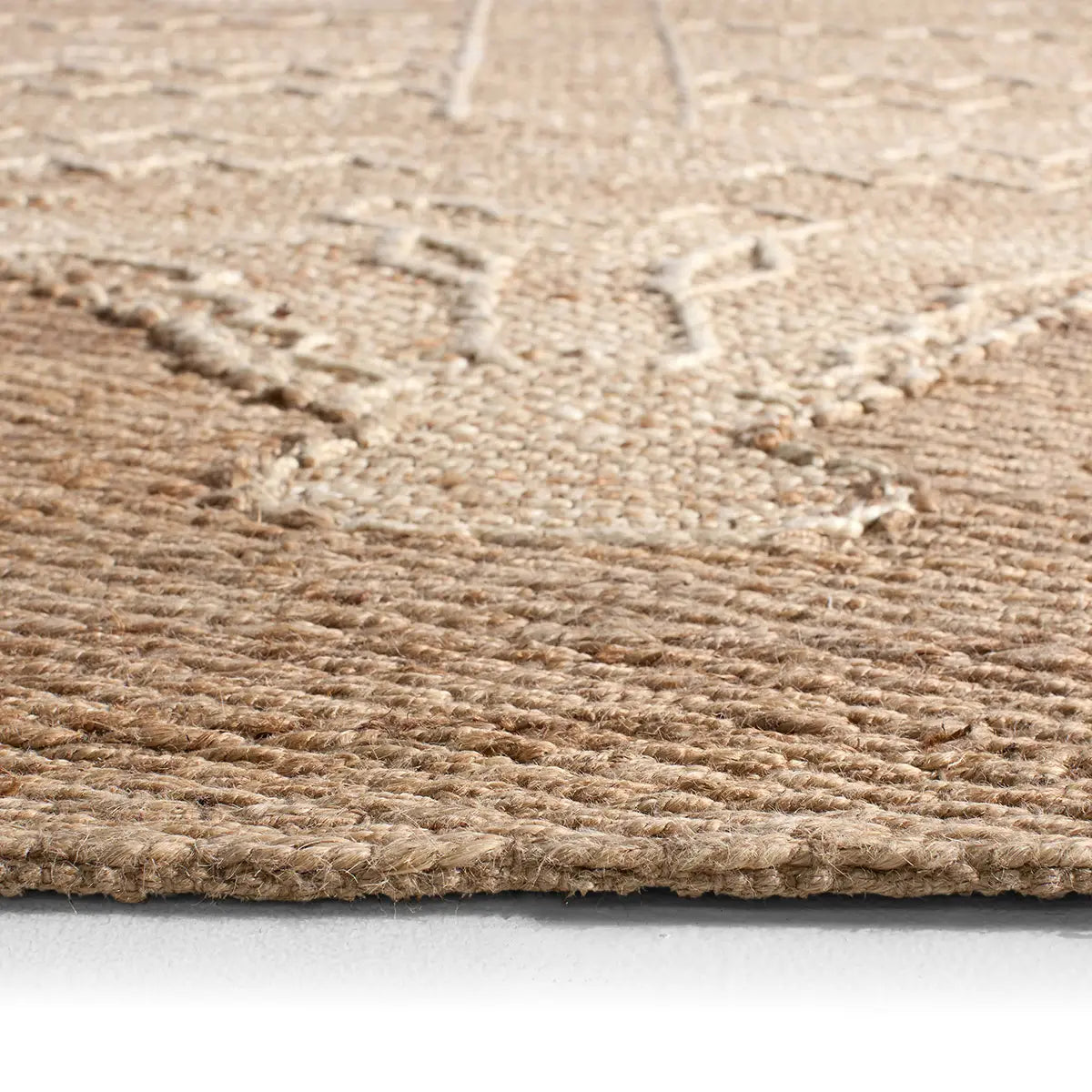 Close-up of a textured beige rug on a light gray floor.