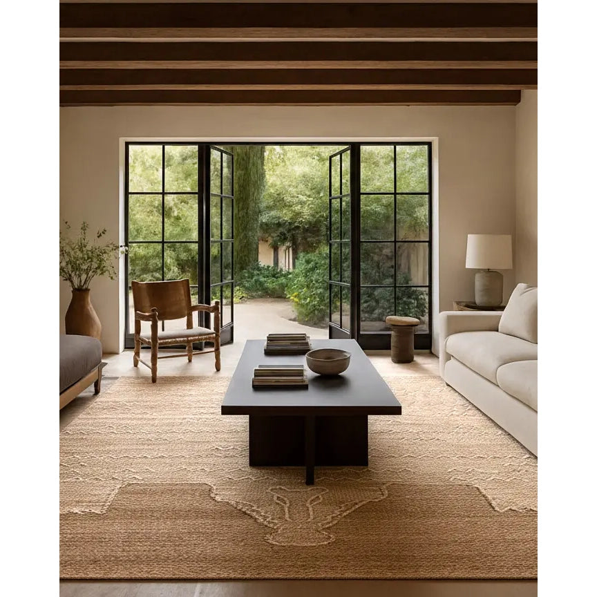 Modern living room with a coffee table, chairs, and a large window view of greenery.