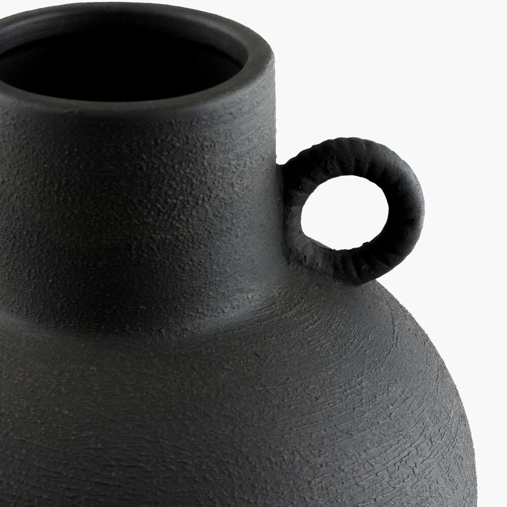 Black textured vase with a handle on a white background