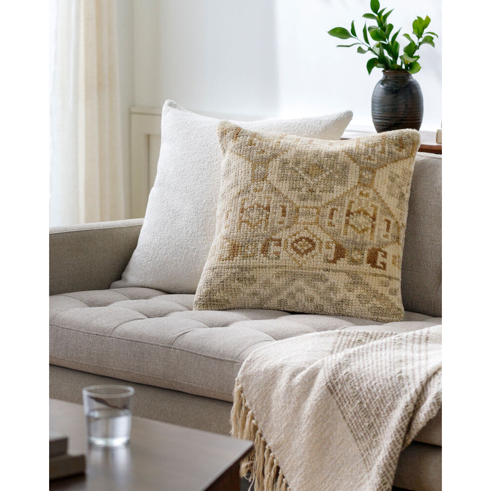Beige pillow with decorative pattern on a beige sofa in a living room setting.