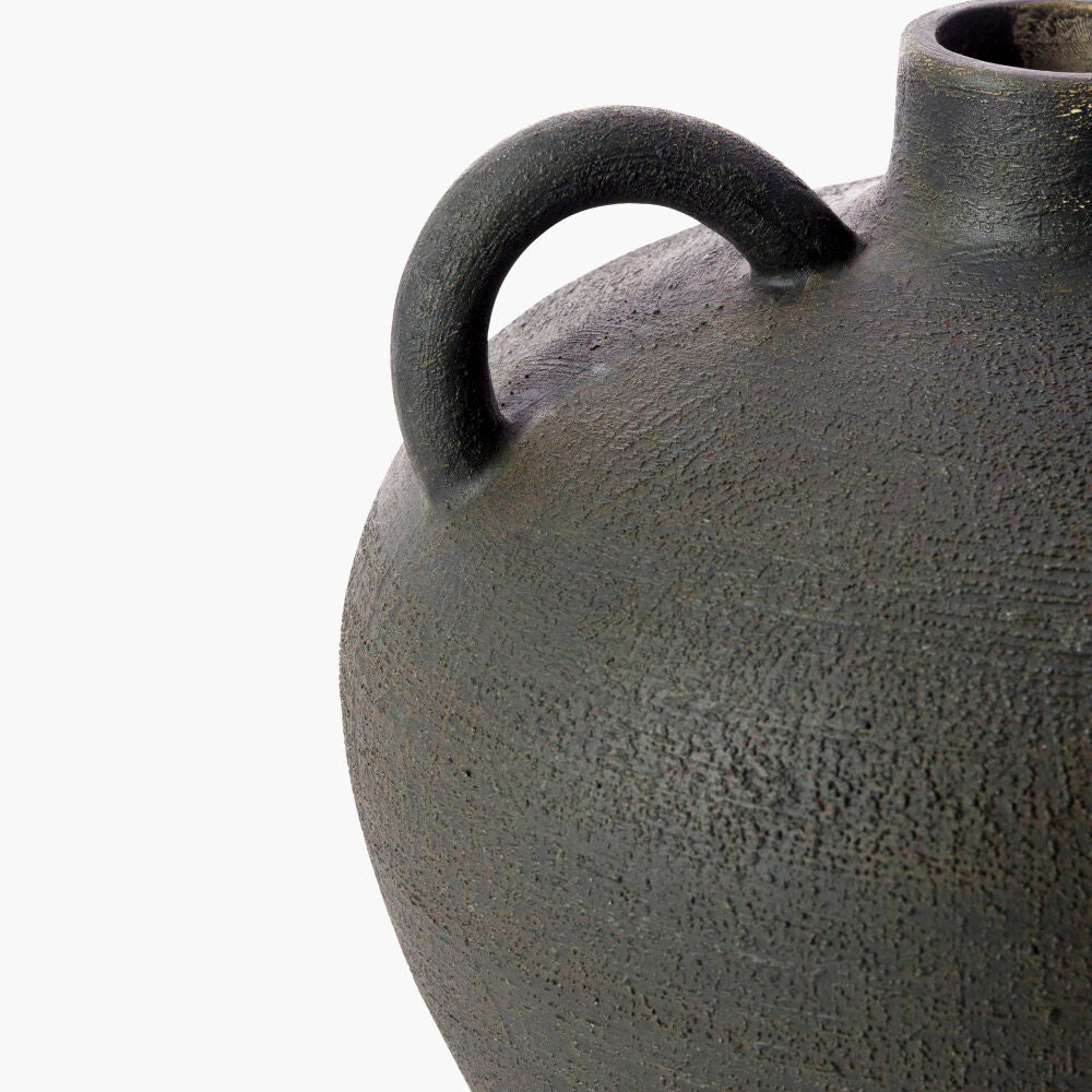 Close-up of a textured black ceramic vase with a handle on a white background