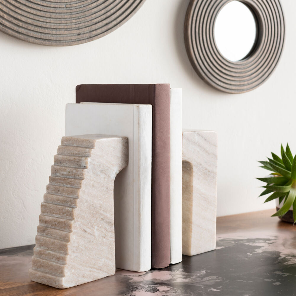 Set of stone bookends on a wooden surface with decorative elements in the background