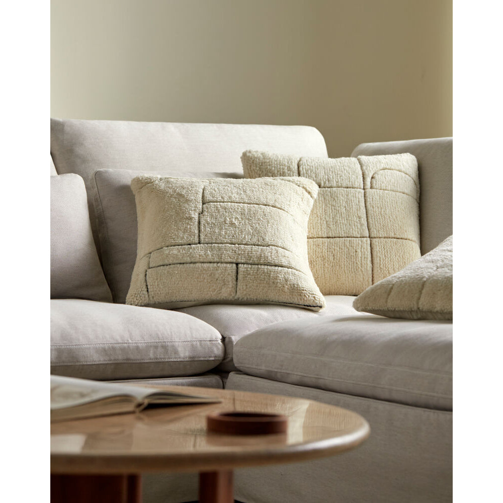Beige sectional sofa with textured pillows in a living room setting.