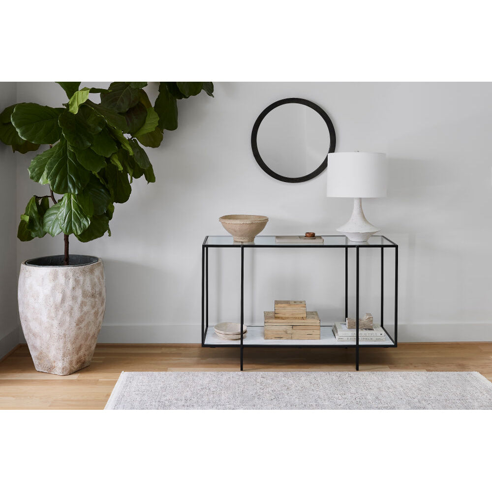 Modern interior with a plant, side table, and lamp against a white wall.
