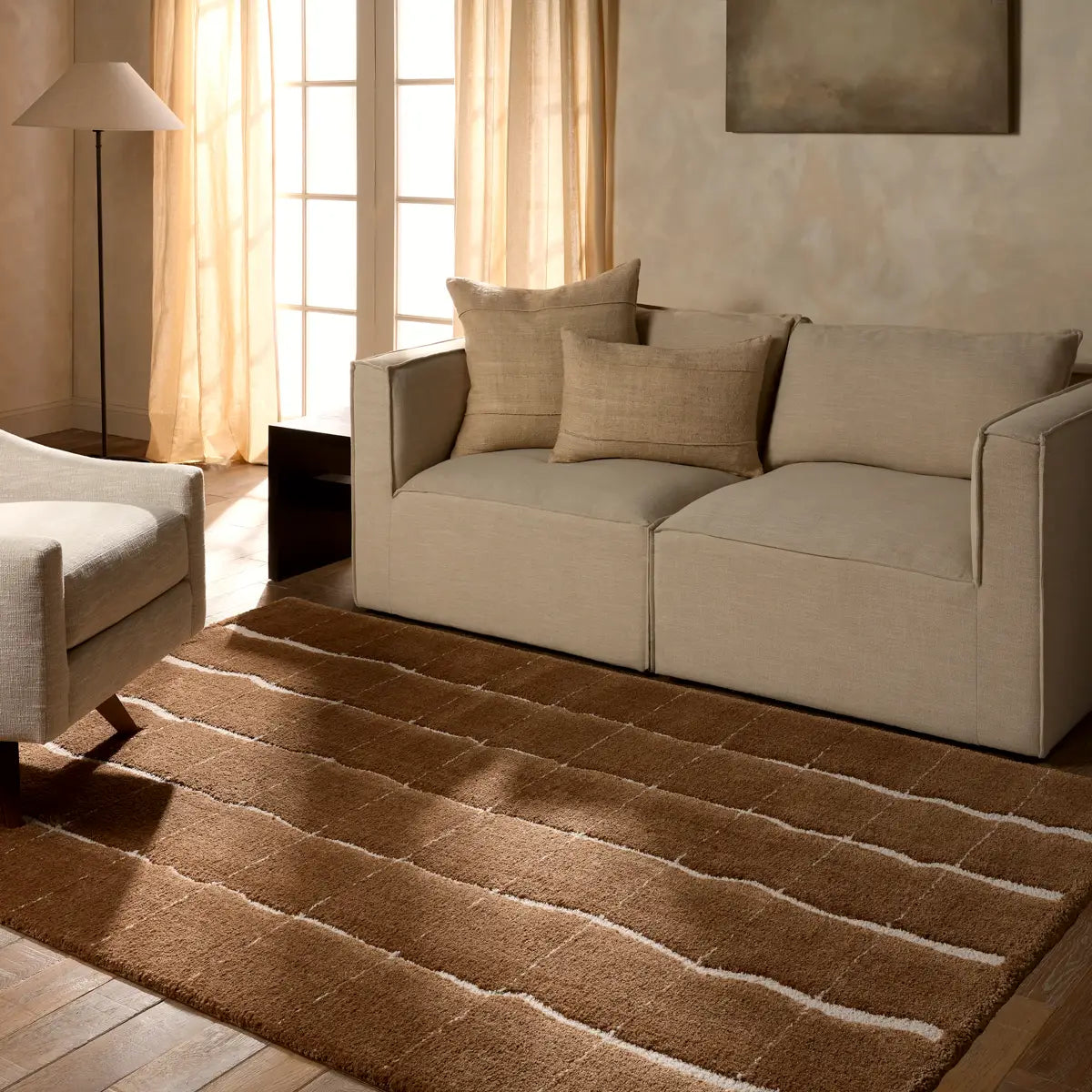 Living room with beige sofa, armchair, and brown rug.