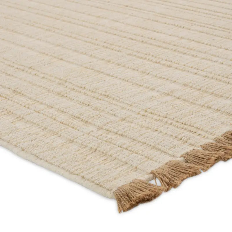 Beige woven rug with tassels on a white background