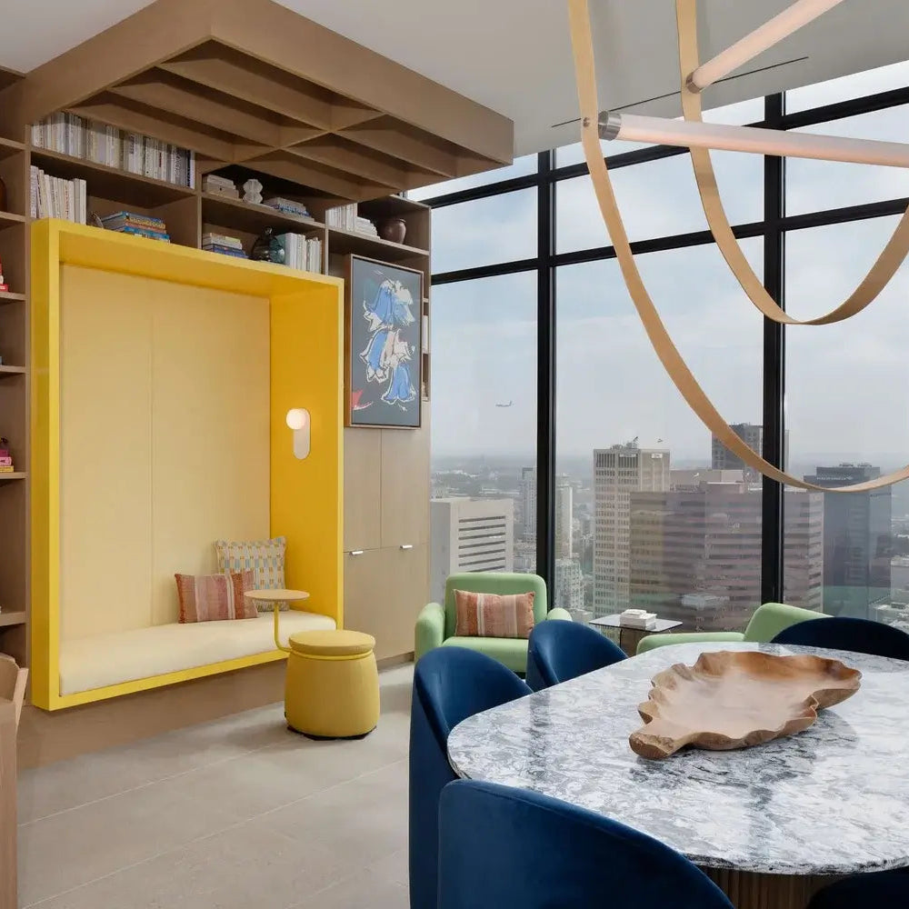 Modern office space with a yellow booth, bookshelves, and large windows.