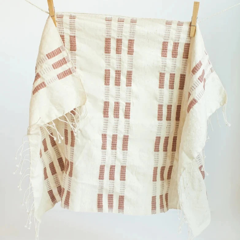 Hand towel with clay and beige pattern draped over a wooden frame against a white background