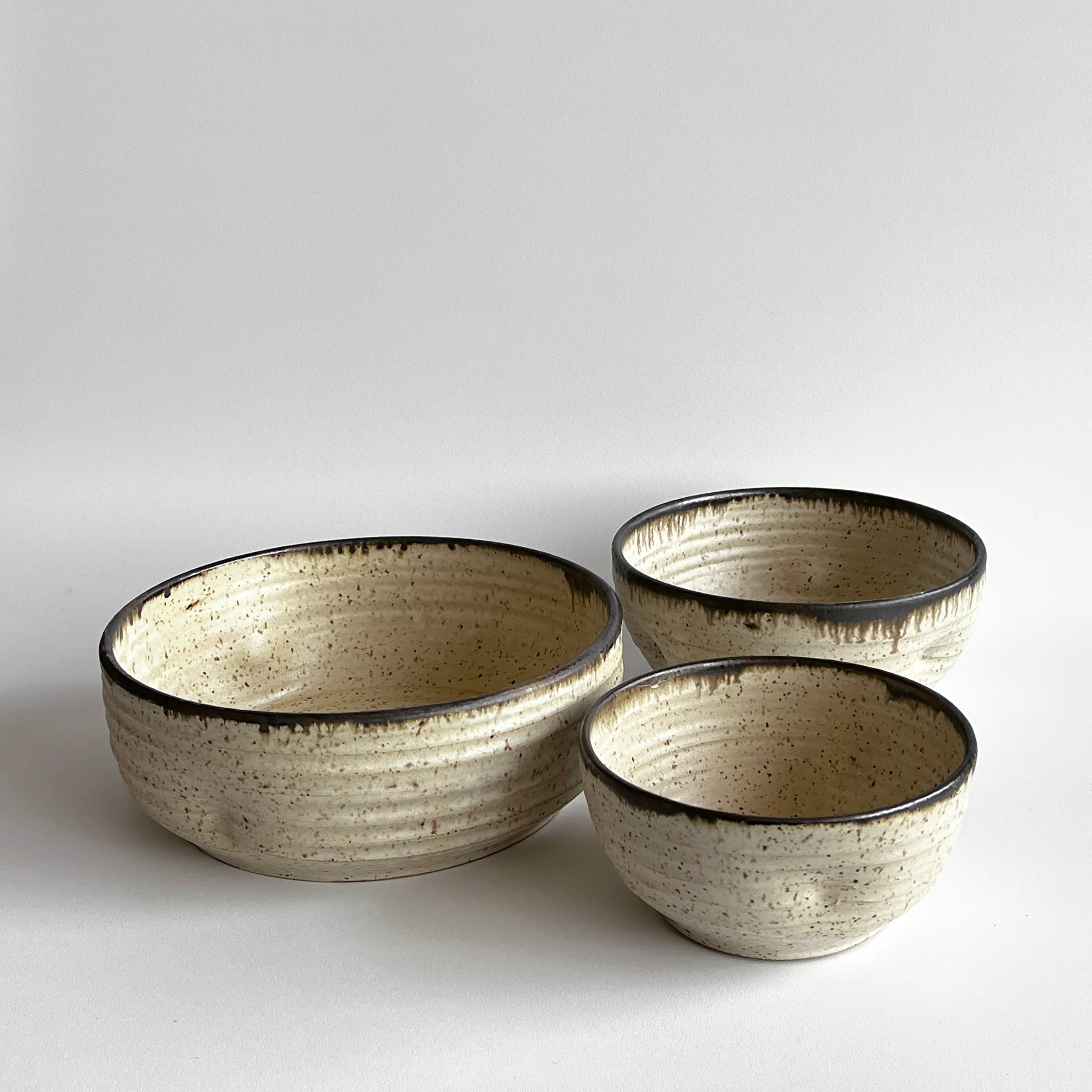 Three ceramic bowls of varying sizes on a light gray background