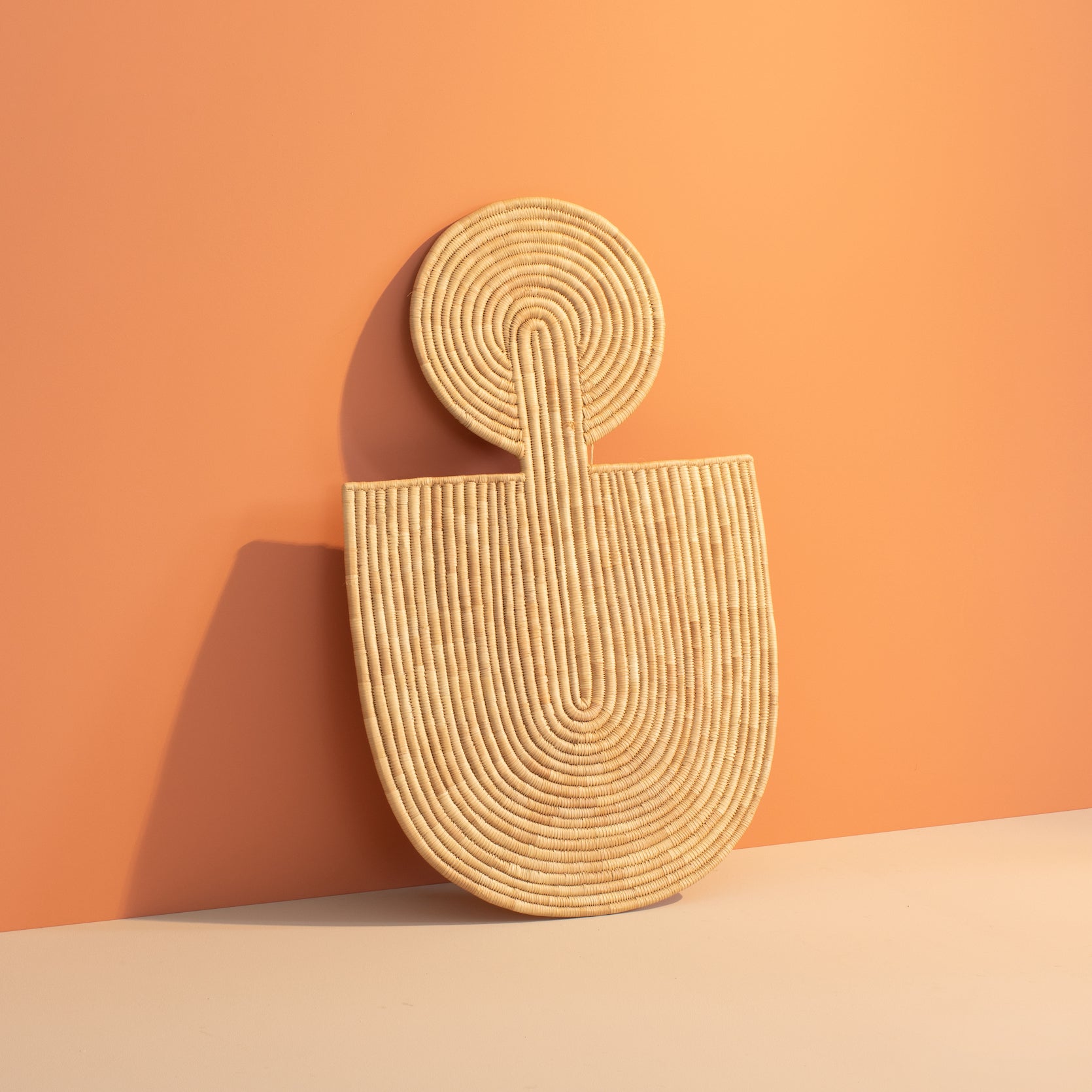 Woven wall art with a geometric design on an orange background