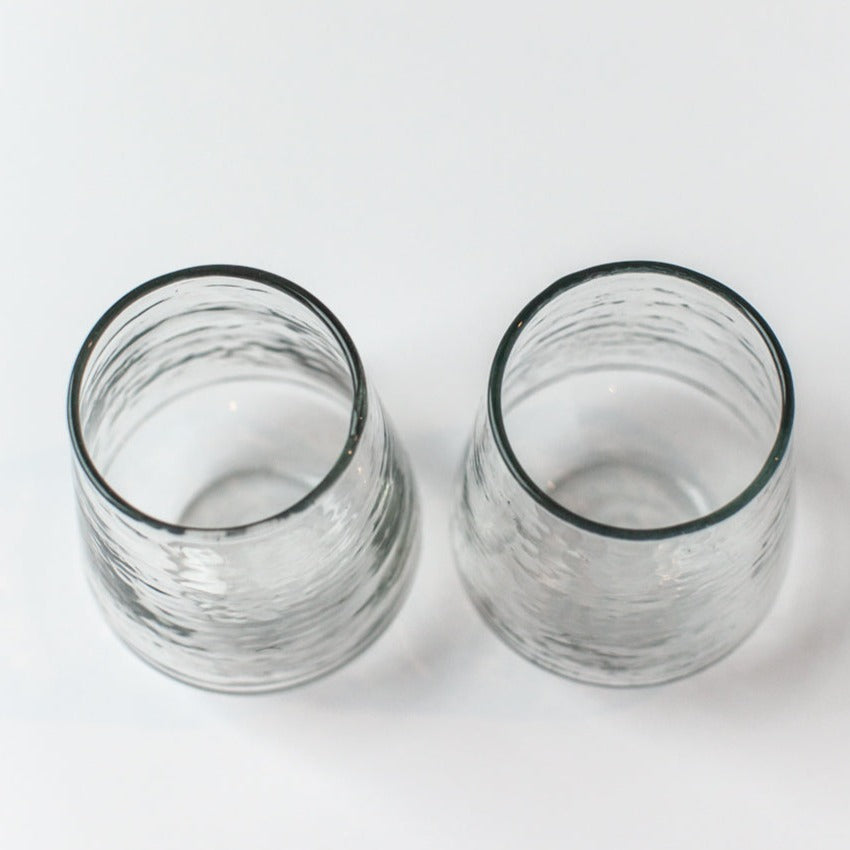 Two clear hammered glass tumblers on a white background