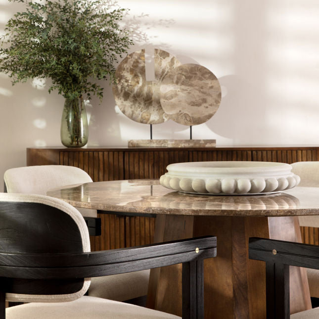 Dining room with marble table, chairs, and decorative elements.