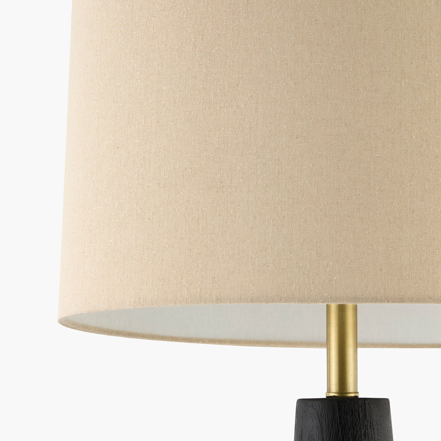 Close-up of a lamp with a beige shade and brass fixture on a white background