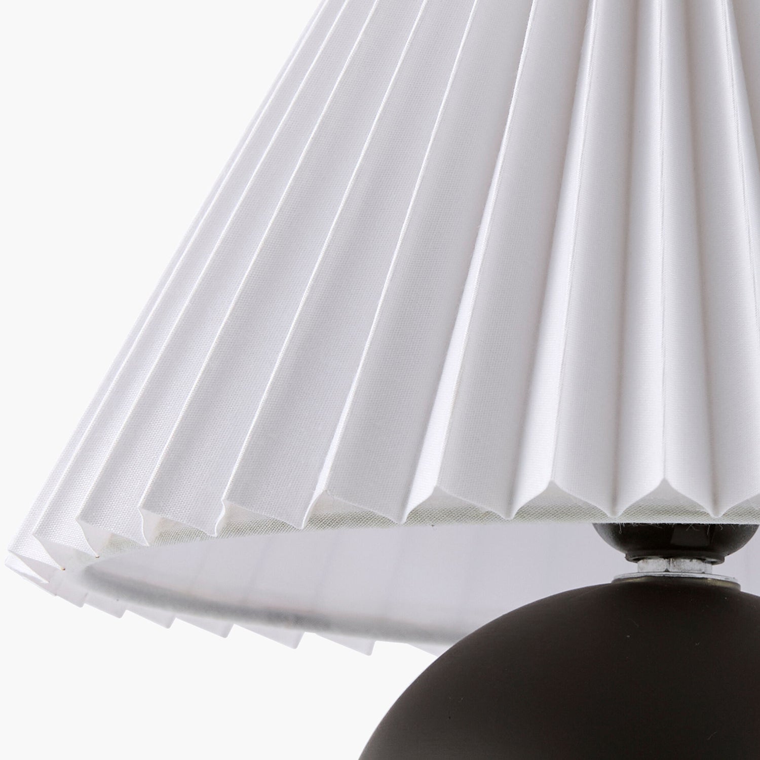 Close-up of a pleated white lampshade with a black base on a white background