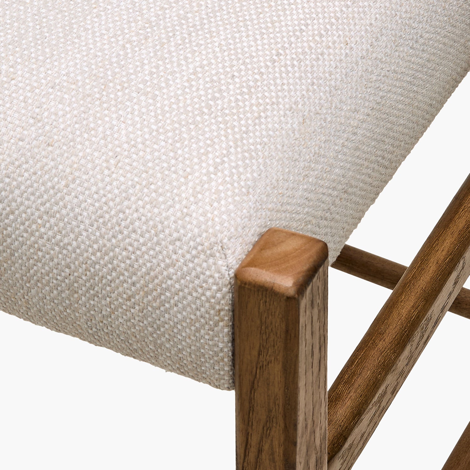 Close-up of a chair with wooden frame and textured beige cushion on a white background