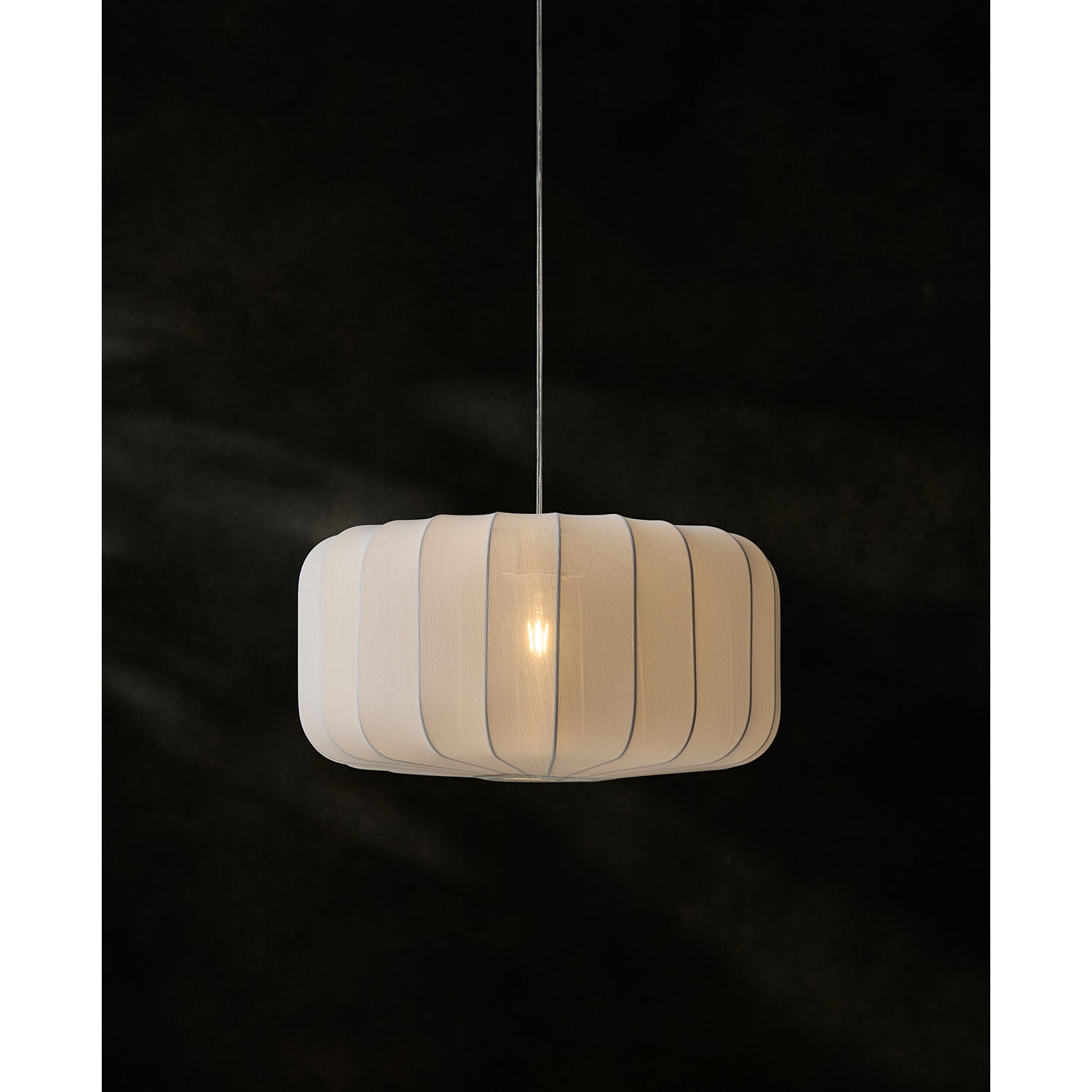 Beige pendant lamp with ribbed design on a black background