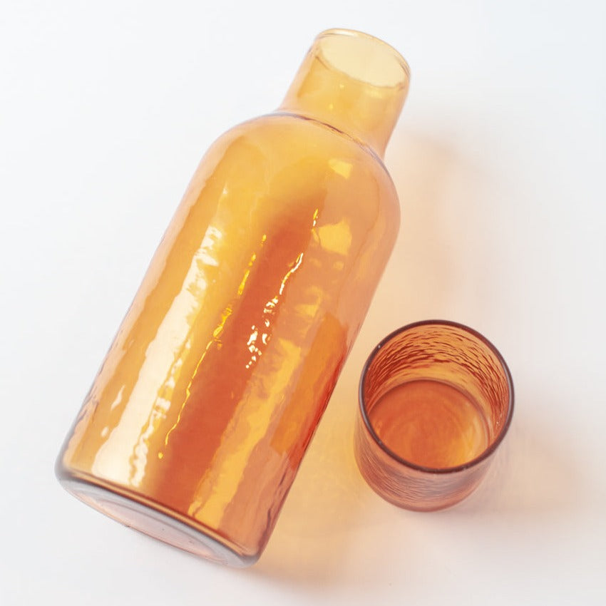 Orange glass carafe and cup on a white background