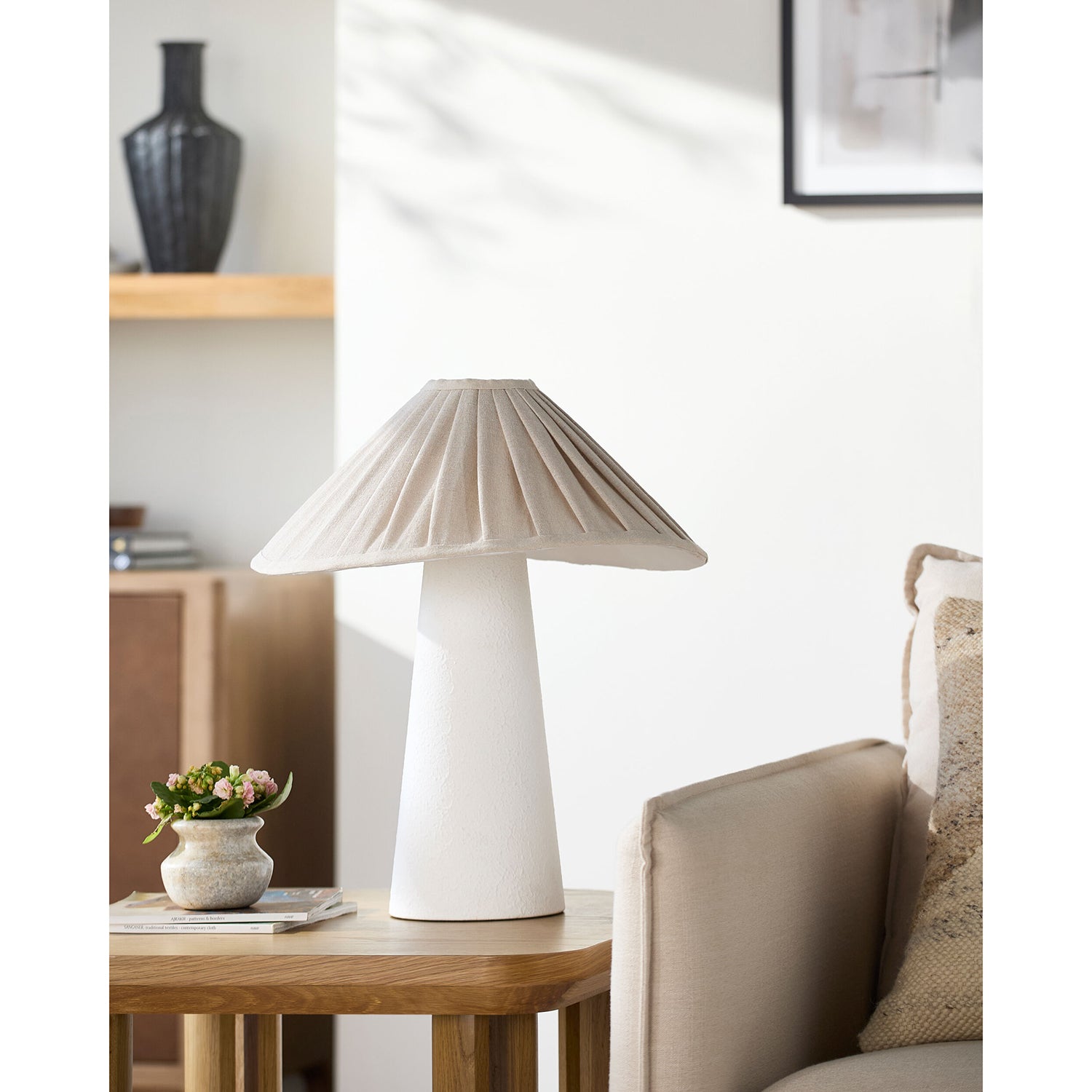 White table lamp on a wooden side table with a cozy living room setting.