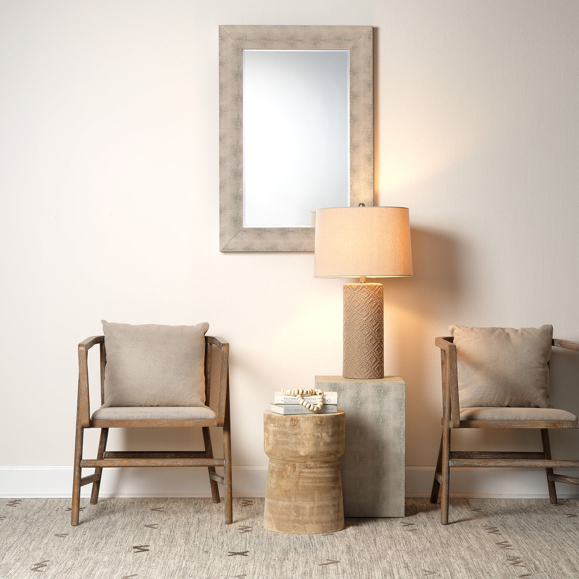 Two wooden chairs with beige cushions, a lamp, and a mirror in a room setting.