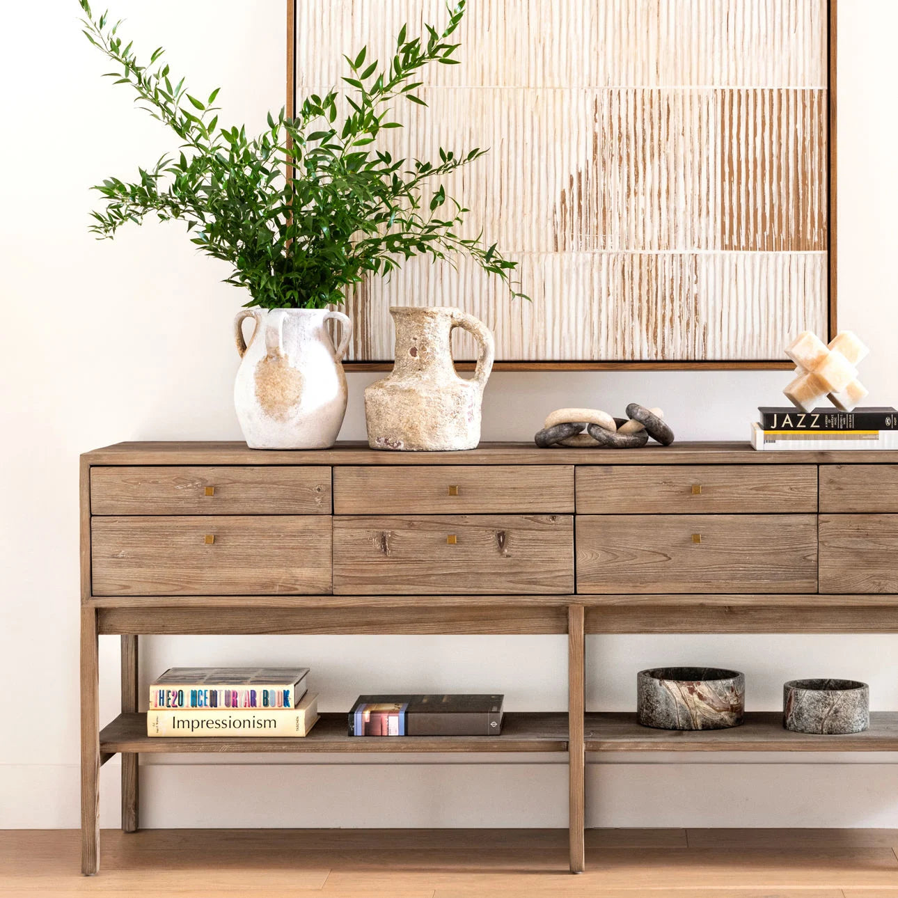 Wooden console table with decorative items against a wall with a geometric pattern.