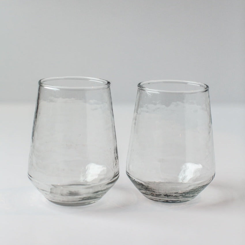 Two clear hammered glass tumblers on a light gray background