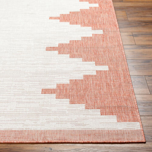 Pink and white geometric patterned rug on a wooden floor