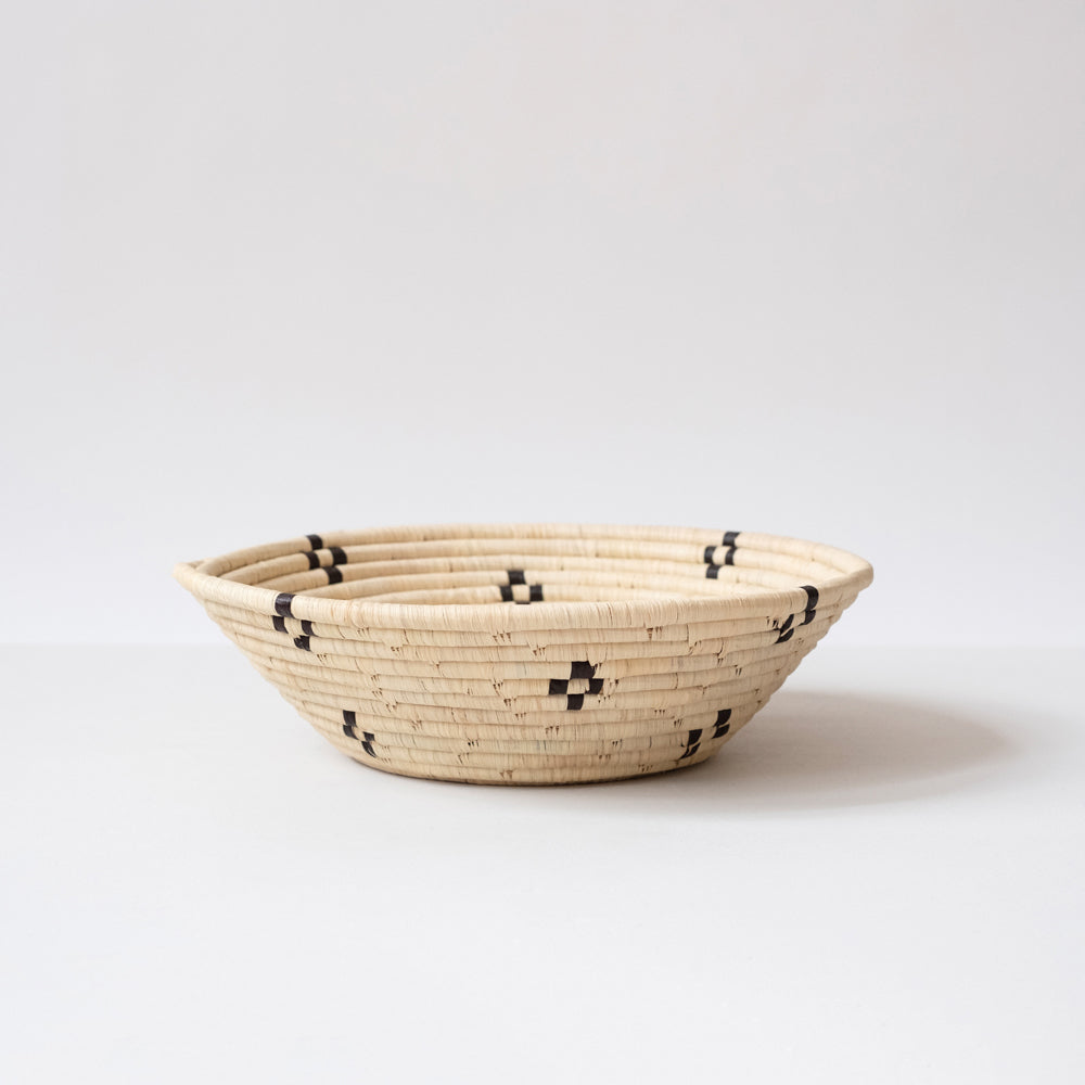 Woven basket with black patterns on a white background