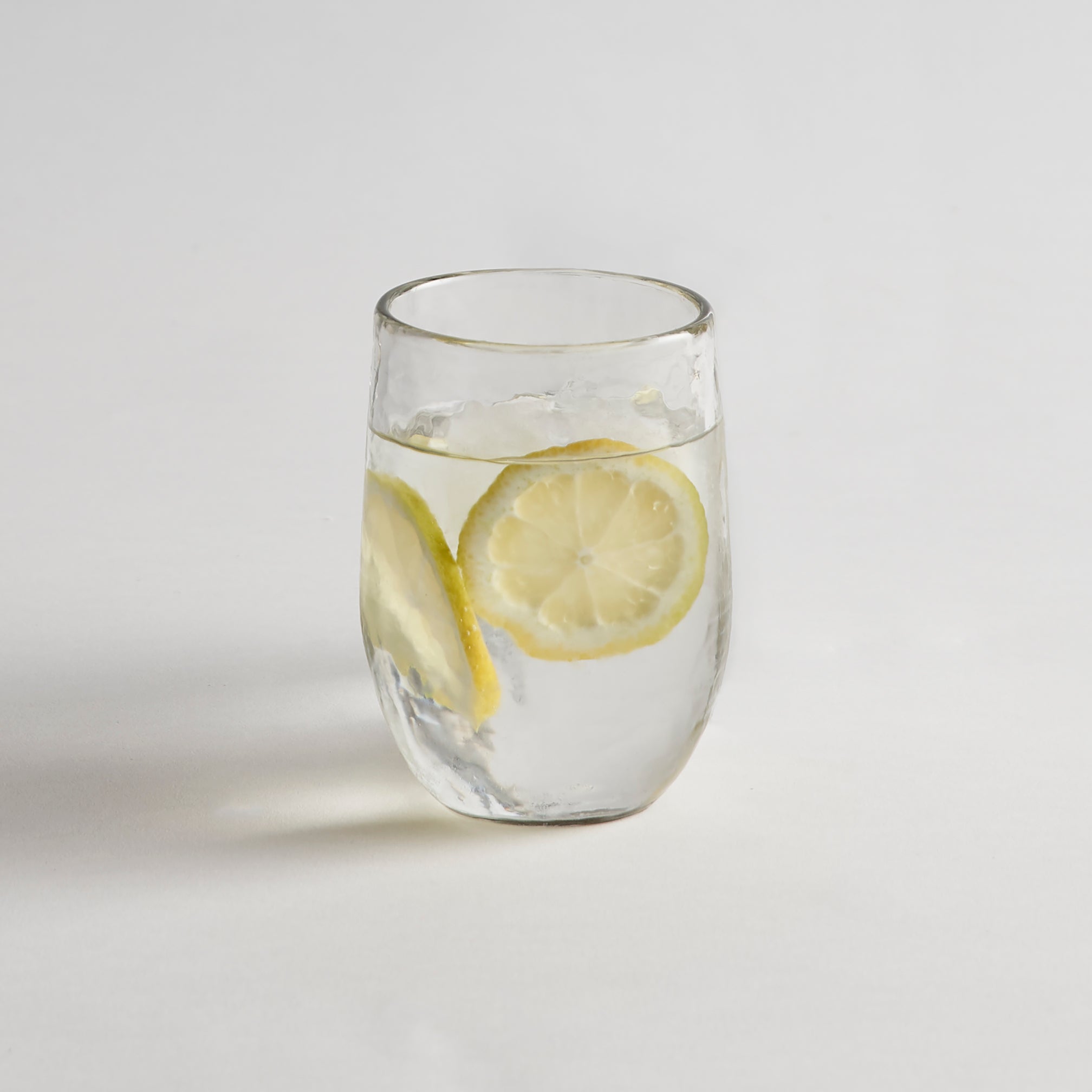 Clear textured glass with lemon slices on a light gray background