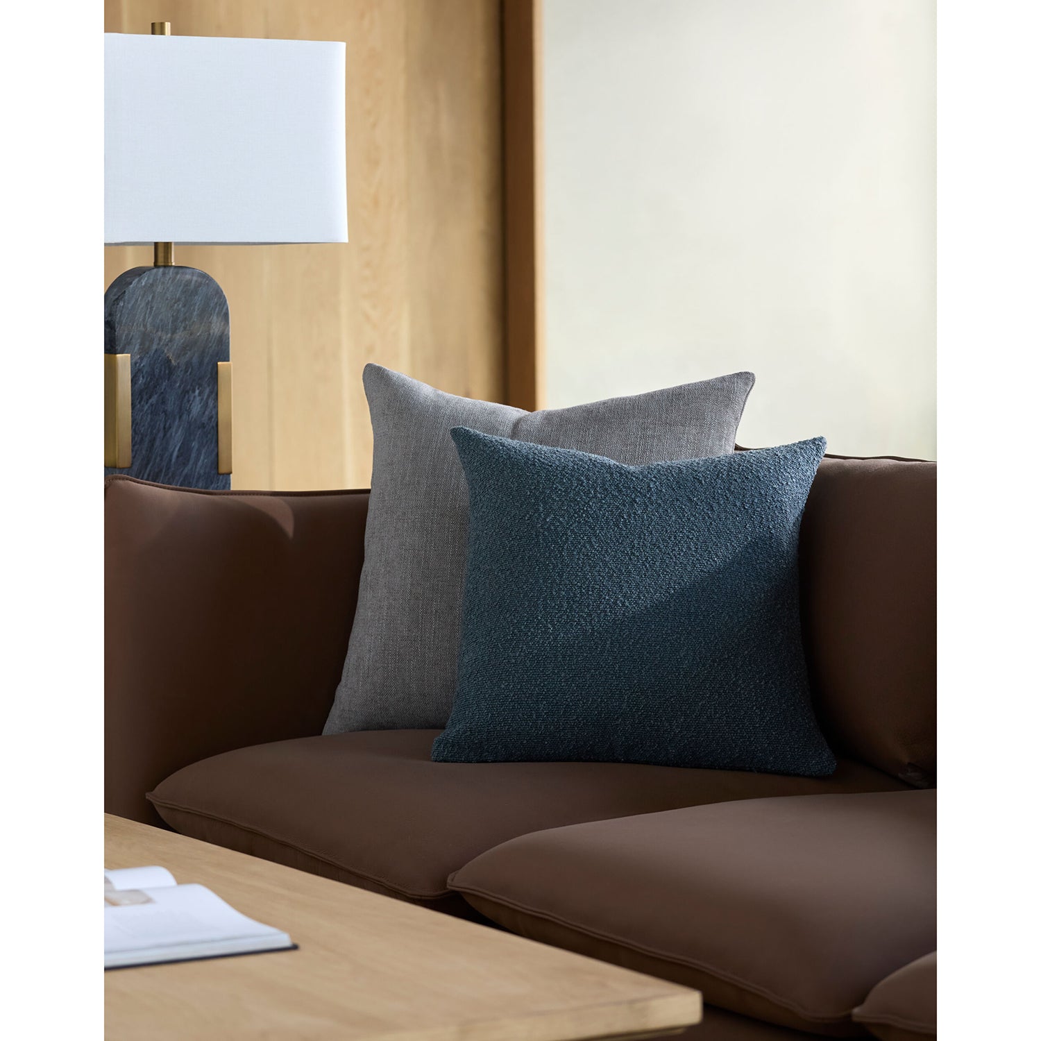 Brown sofa with blue and gray cushions in a living room setting.