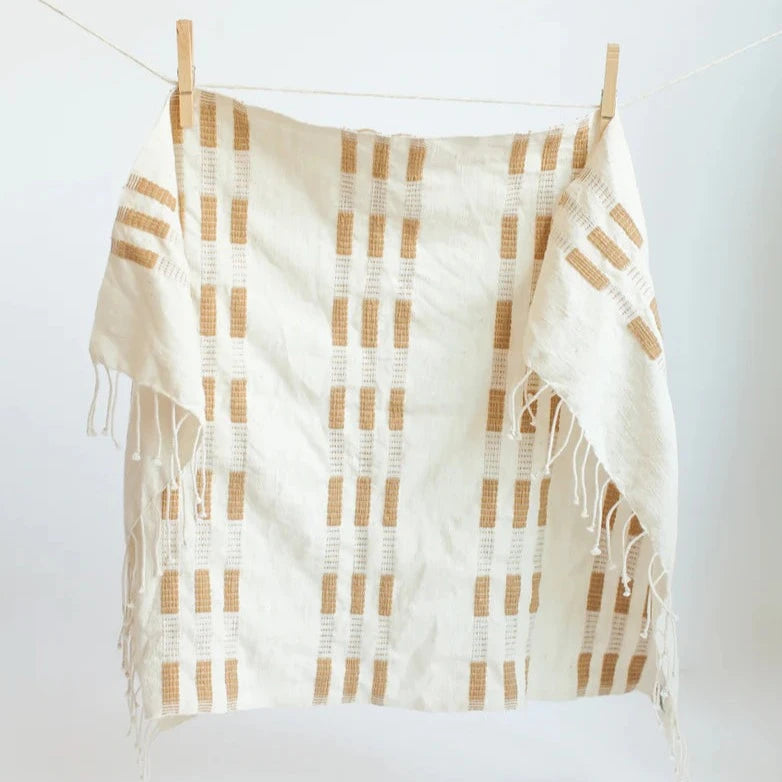 Patterned hand towel with white and brown pattern hanging on a clothesline against a white background
