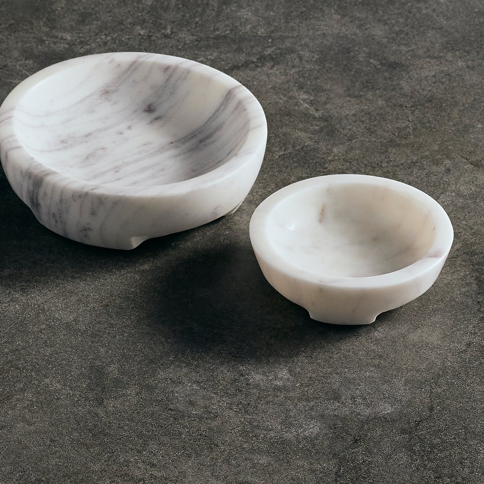 Two marble bowls on a dark stone surface