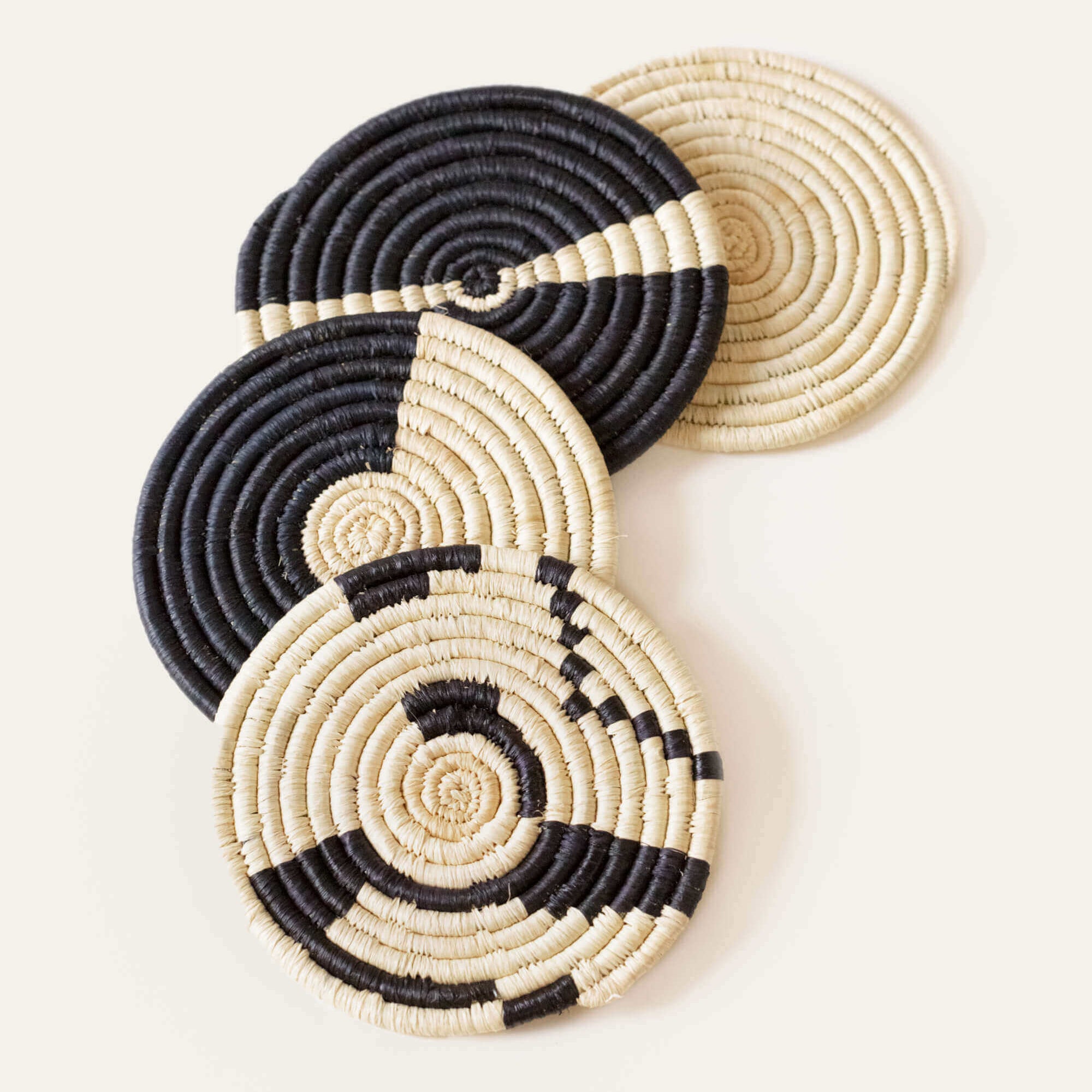 Set of black and beige woven coasters on a light background