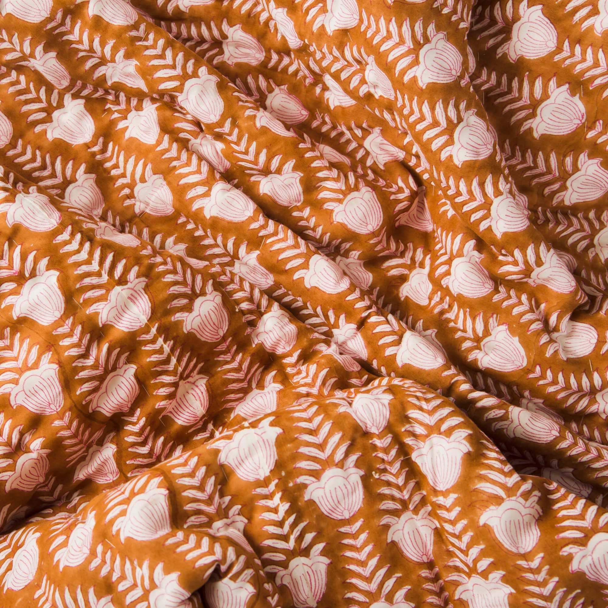 Close-up of fabric with white floral pattern on a rust-colored background