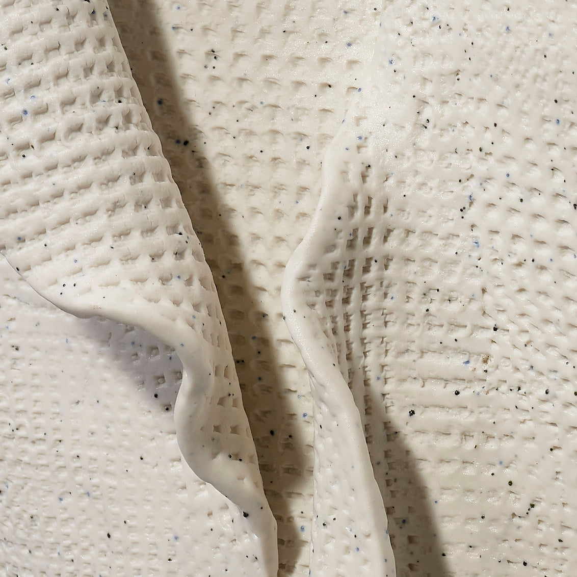 Close-up of textured white material with specks on a light background