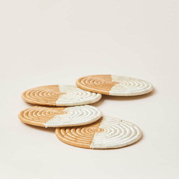 Set of four round woven coasters with a two-tone design on a beige background
