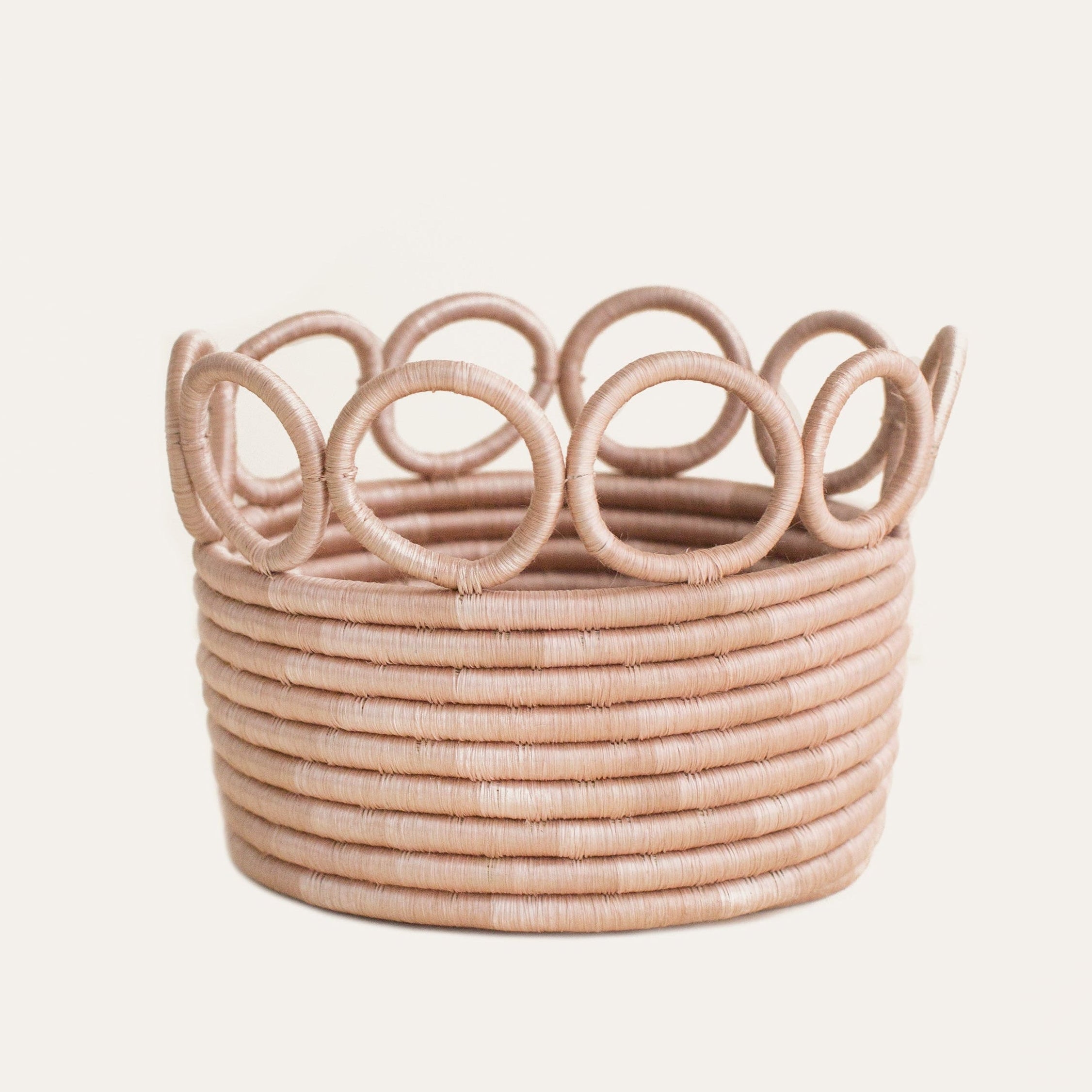 Woven basket with decorative top on a light pink background