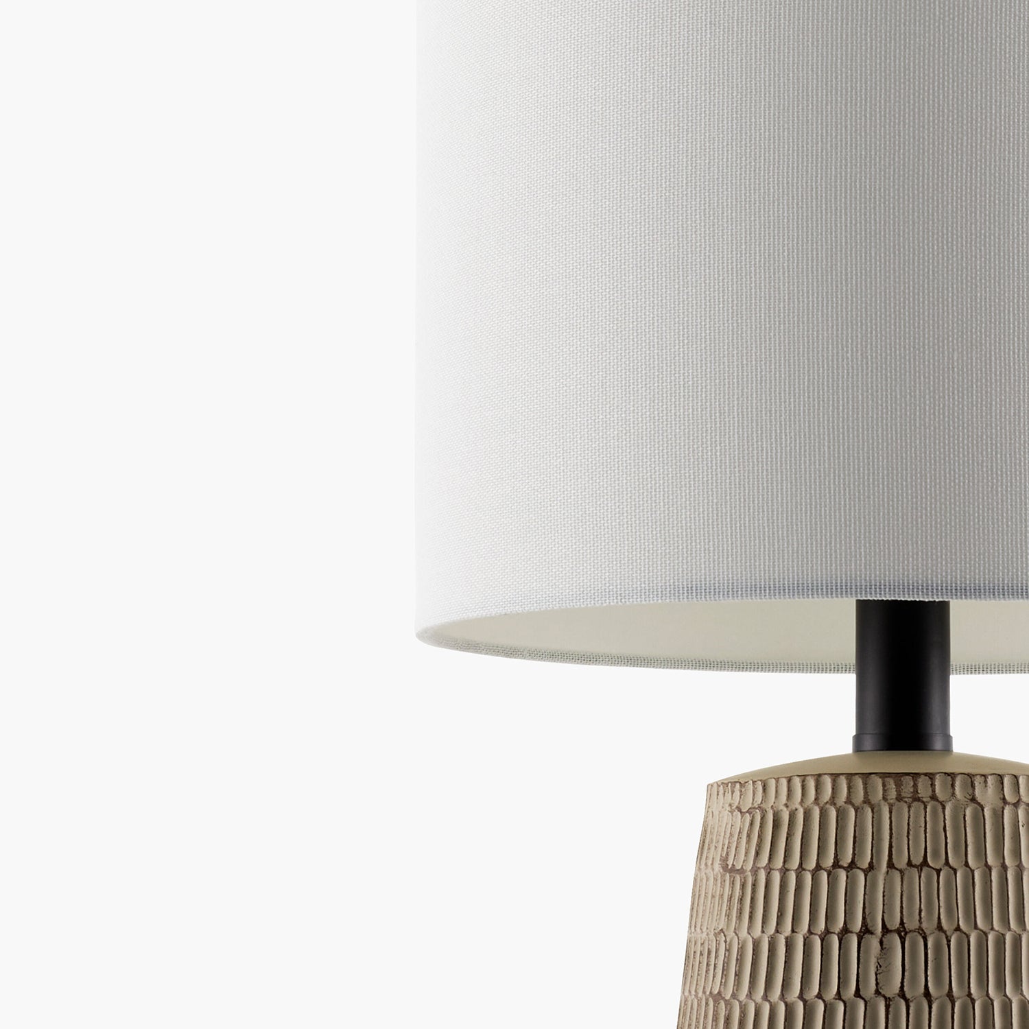 Table lamp with textured beige base and white shade on a white background