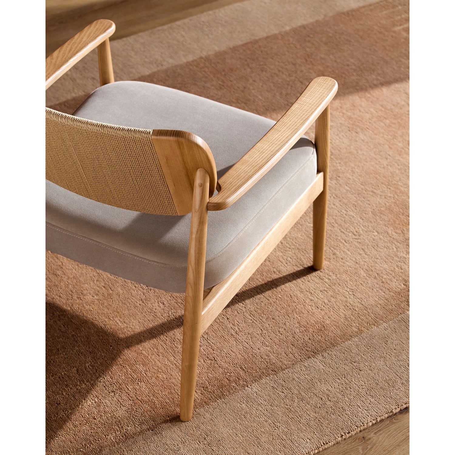 Wooden chair with light gray cushion on a patterned rug