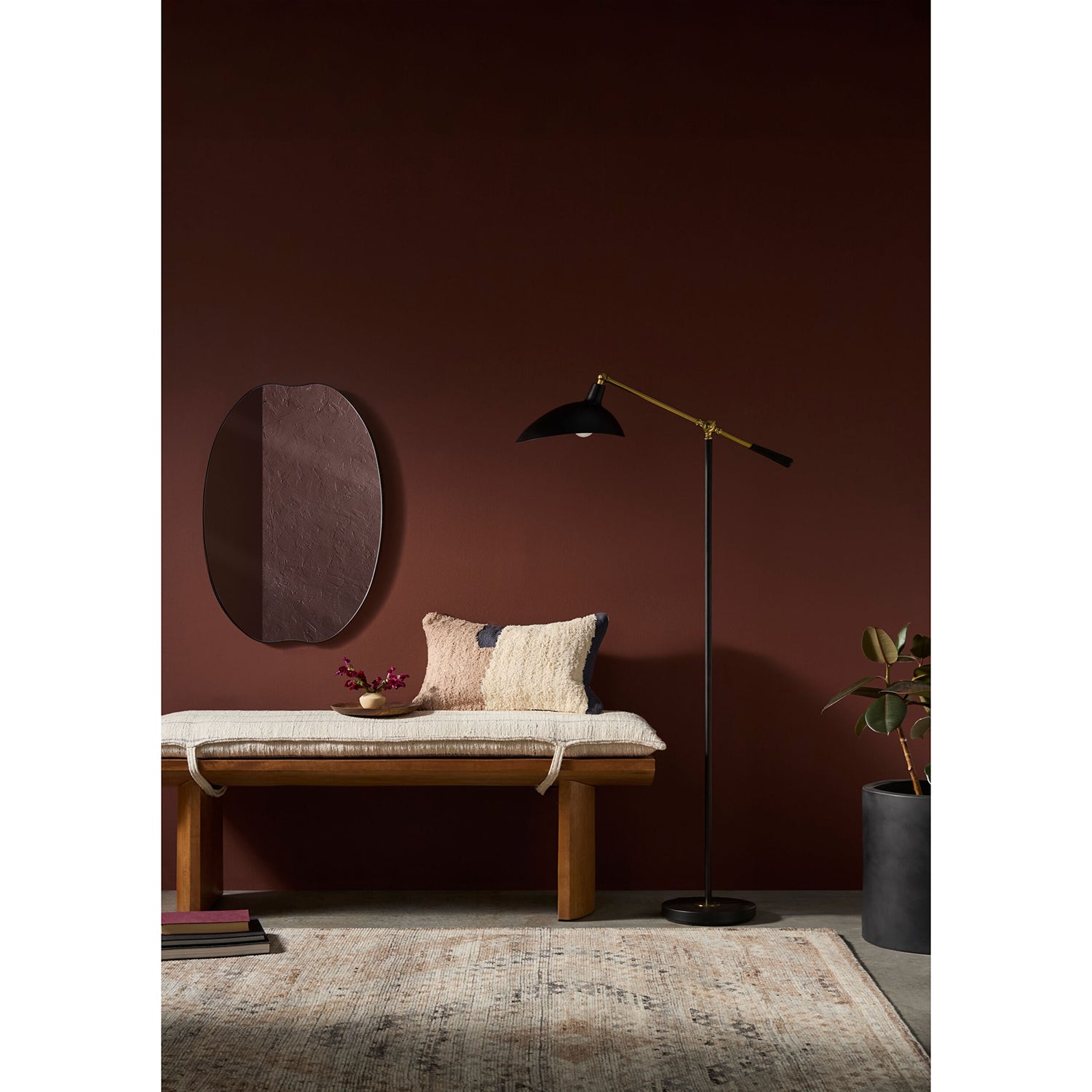 Modern interior with a wooden bench, floor lamp, and decorative items against a dark red wall.